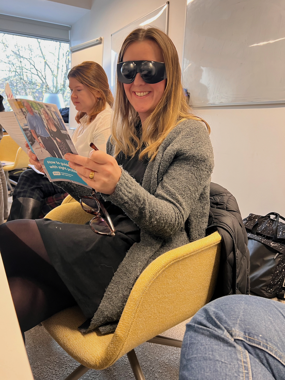 Laura Laura wearing glasses simulating tunnel vision, trying to read a pamphlet.